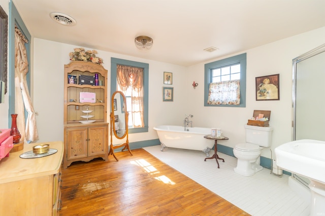 bathroom with visible vents, a freestanding bath, and wood finished floors