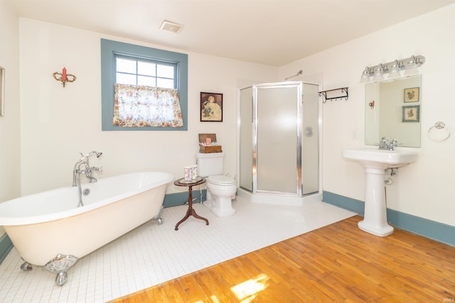 bathroom with visible vents, a freestanding bath, toilet, a stall shower, and wood finished floors