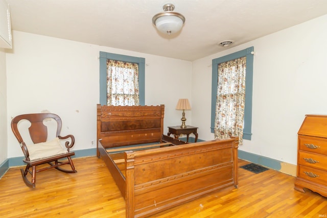 bedroom featuring visible vents, light wood-style flooring, and baseboards