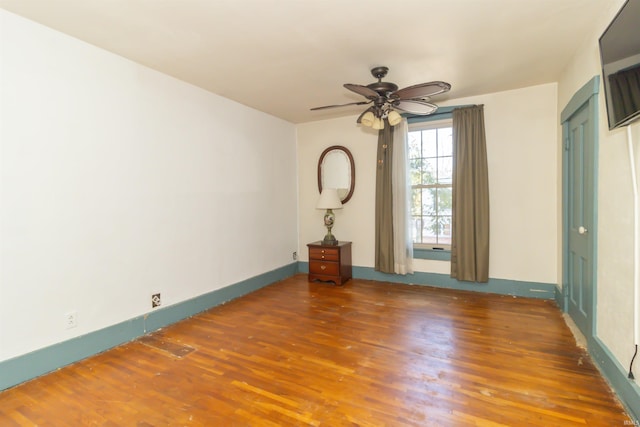 spare room featuring ceiling fan, baseboards, and wood finished floors