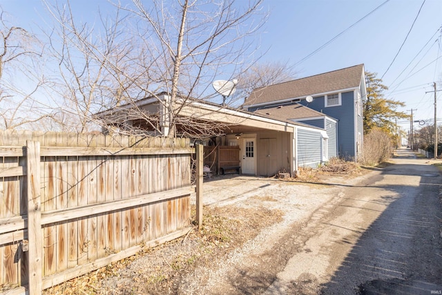 view of home's exterior with roof with shingles and fence