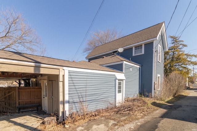 view of property exterior with roof with shingles and fence