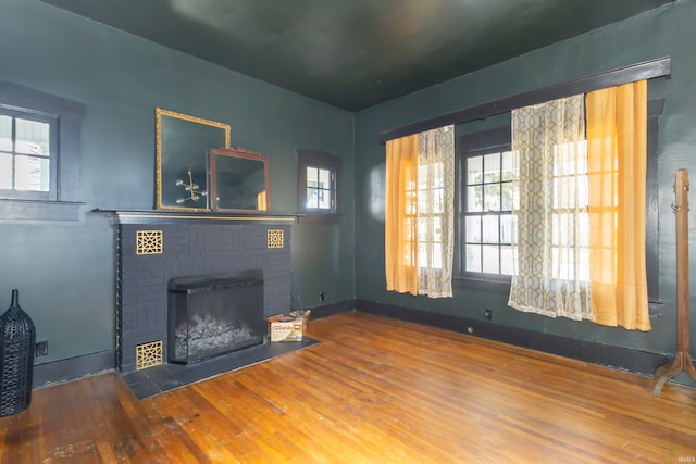 living area with a brick fireplace, baseboards, and wood finished floors