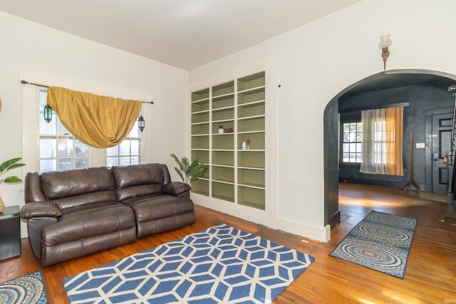 living room featuring arched walkways, wood-type flooring, and a wealth of natural light