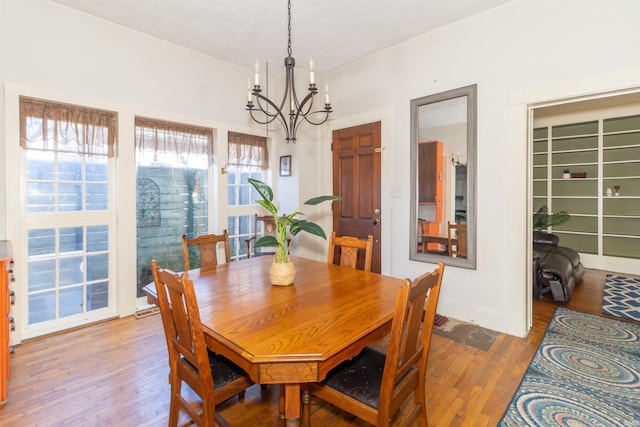 dining area featuring baseboards, a chandelier, and wood finished floors