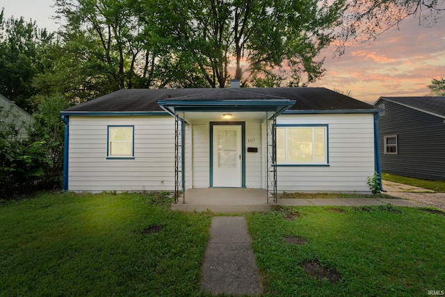 view of front of property featuring a porch, a lawn, and a chimney