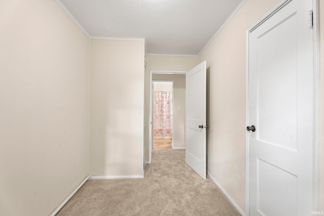 hall with light colored carpet, crown molding, and baseboards