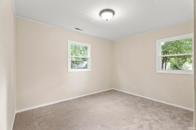 unfurnished room featuring carpet floors, baseboards, visible vents, and a wealth of natural light