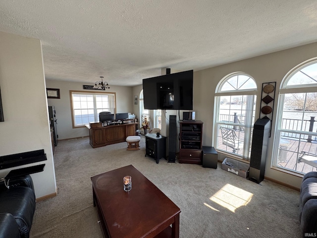 carpeted living room featuring a textured ceiling, baseboards, and a notable chandelier