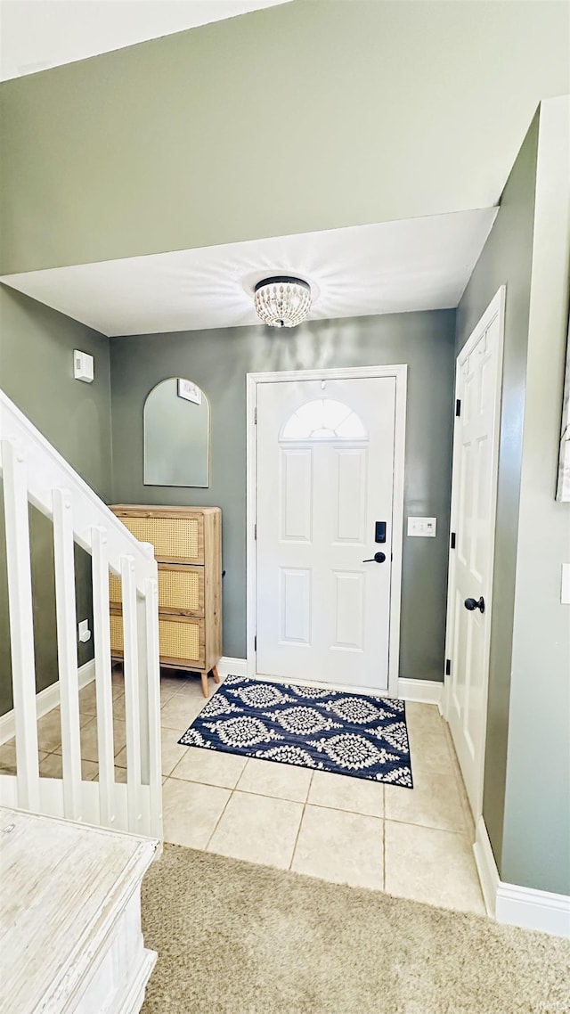 entryway with stairs, baseboards, and light tile patterned floors