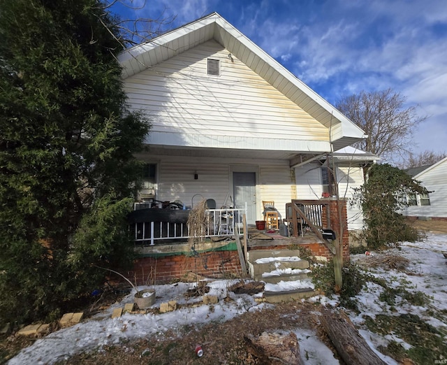 snow covered house featuring a porch