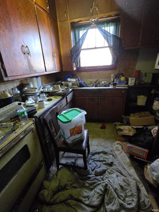 kitchen featuring light tile patterned floors, range with electric stovetop, and a sink