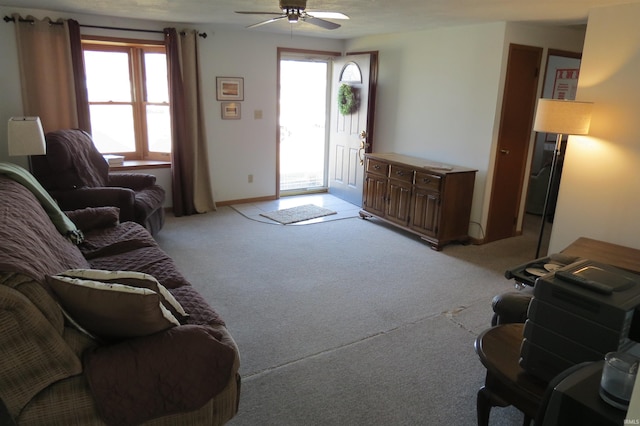 living room featuring baseboards, a ceiling fan, and light colored carpet