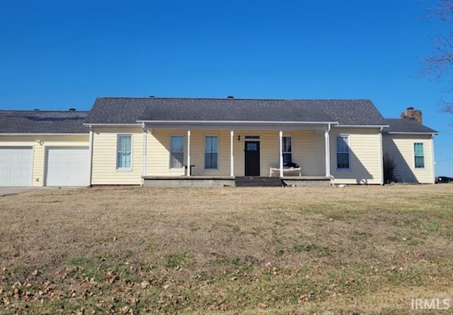 rear view of house featuring a garage, covered porch, a chimney, and a yard