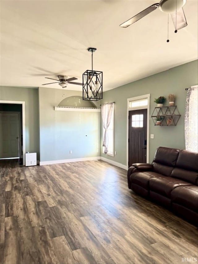 unfurnished living room featuring ceiling fan, dark wood-type flooring, and baseboards