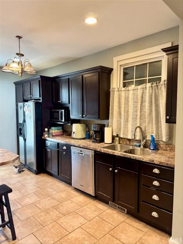 kitchen with a chandelier, stainless steel appliances, a sink, visible vents, and dark brown cabinets