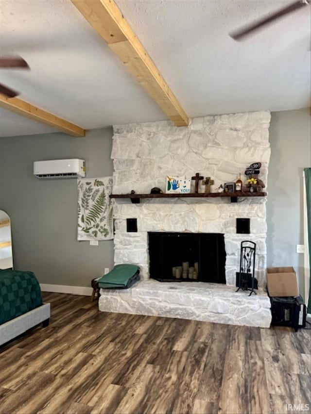 unfurnished living room with a fireplace, beam ceiling, an AC wall unit, and wood finished floors