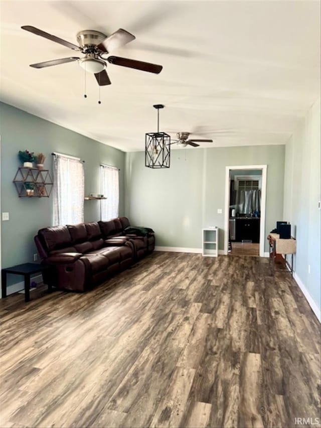 living room with dark wood-style floors, ceiling fan, and baseboards