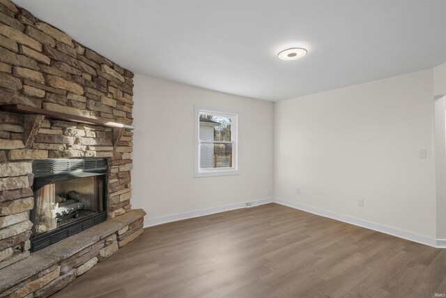 unfurnished living room featuring a fireplace, baseboards, and wood finished floors