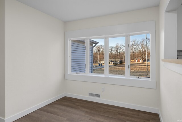 spare room featuring baseboards, visible vents, and dark wood finished floors