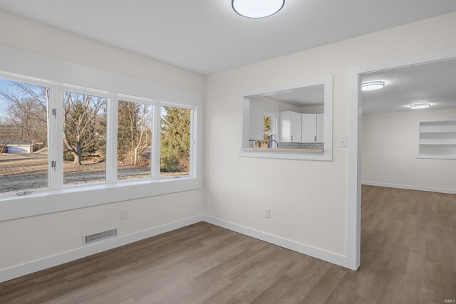 spare room with baseboards, visible vents, and wood finished floors