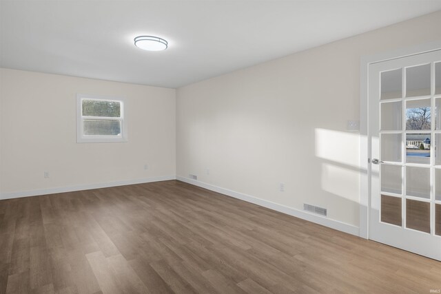 spare room with visible vents, baseboards, and wood finished floors