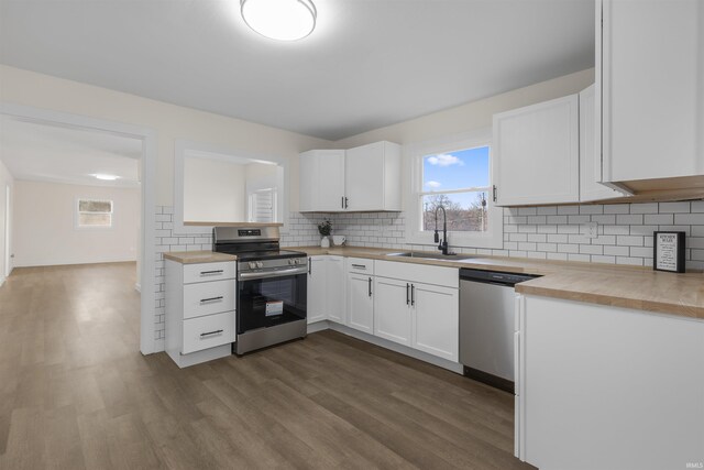 kitchen featuring dark wood-style floors, butcher block countertops, stainless steel appliances, and a sink