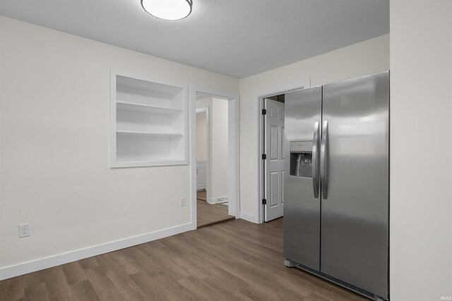 kitchen with built in shelves, baseboards, wood finished floors, and stainless steel fridge with ice dispenser