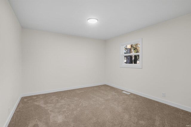 carpeted spare room with visible vents and baseboards