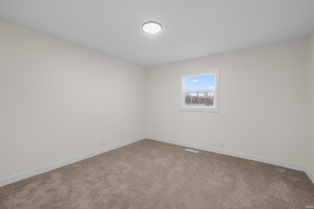 unfurnished room with carpet floors, visible vents, and baseboards