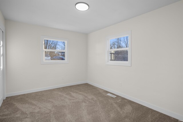 carpeted empty room featuring visible vents and baseboards