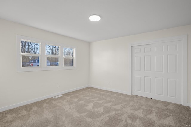 unfurnished bedroom with carpet, a closet, visible vents, and baseboards