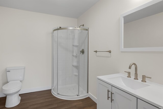 bathroom with a stall shower, wood finished floors, toilet, and baseboards