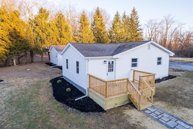 back of property featuring a wooden deck and roof with shingles