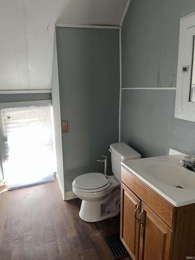 bathroom with toilet, baseboards, wood finished floors, and vanity