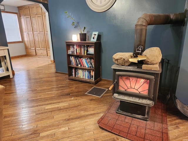 interior space with visible vents, wood finished floors, a wood stove, and baseboards