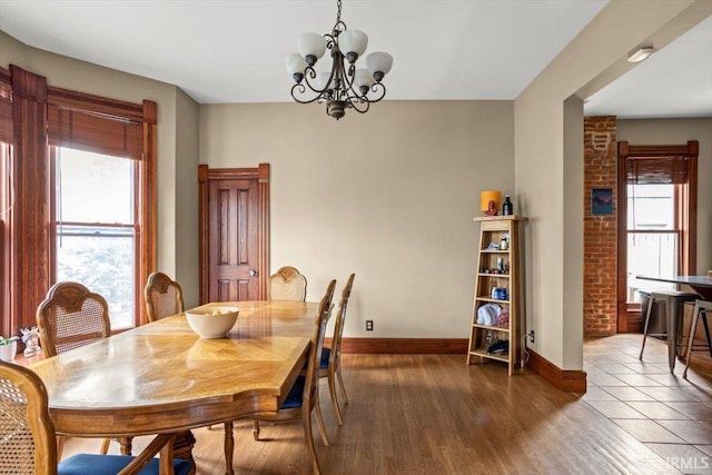 dining area featuring a notable chandelier, baseboards, and wood finished floors