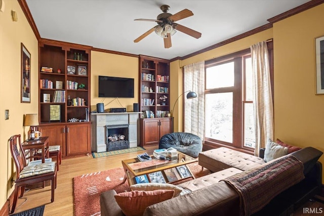 living room with ornamental molding, a high end fireplace, plenty of natural light, and wood finished floors