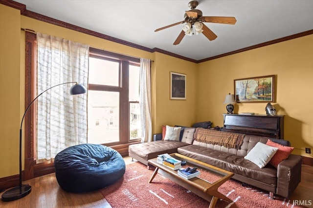 living area with crown molding, baseboards, wood finished floors, and a healthy amount of sunlight