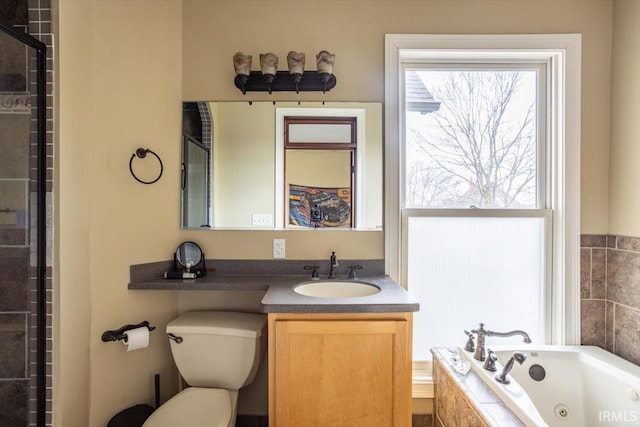 bathroom featuring toilet, a tub with jets, vanity, and a healthy amount of sunlight