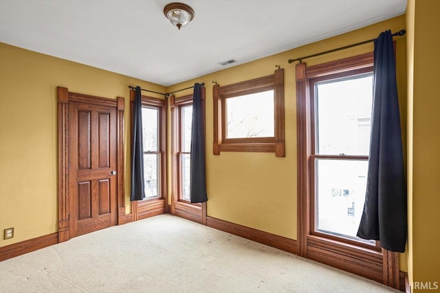 carpeted empty room with visible vents and baseboards