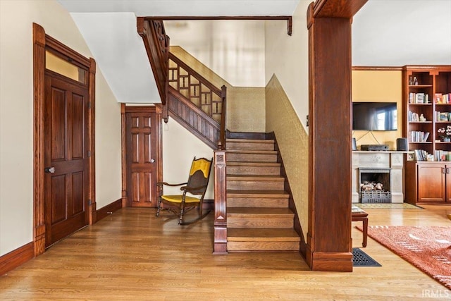 stairs featuring a fireplace, baseboards, and wood finished floors