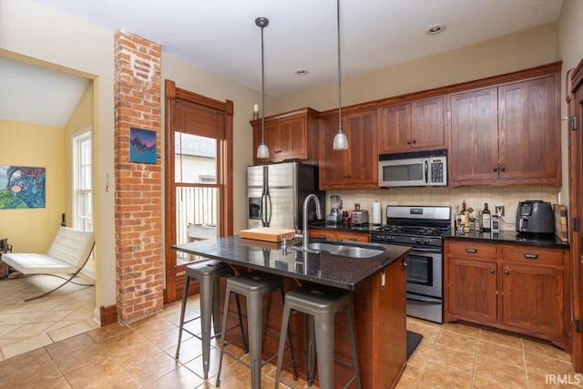 kitchen featuring tasteful backsplash, a center island with sink, a breakfast bar, stainless steel appliances, and a sink