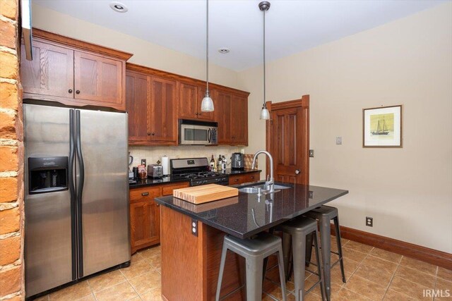 kitchen featuring a breakfast bar area, tasteful backsplash, appliances with stainless steel finishes, a kitchen island with sink, and a sink