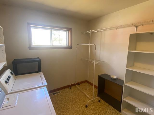 clothes washing area featuring washing machine and dryer, visible vents, and baseboards