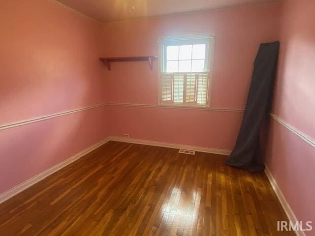 empty room with visible vents, baseboards, and hardwood / wood-style flooring