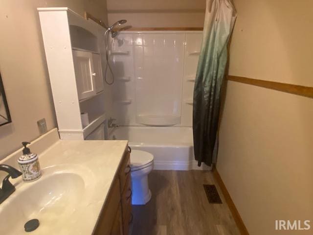 bathroom featuring visible vents, toilet, wood finished floors, shower / bath combination with curtain, and vanity