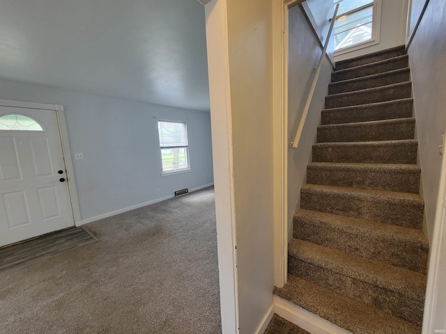carpeted foyer featuring stairs, baseboards, and visible vents