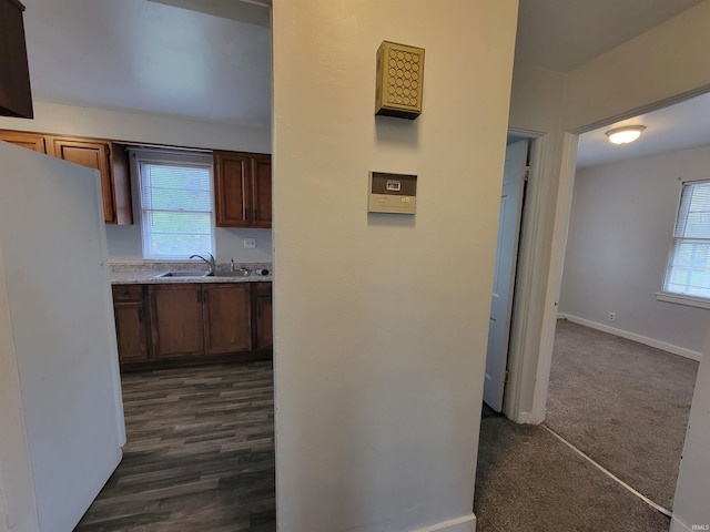 corridor with a sink, baseboards, and a healthy amount of sunlight