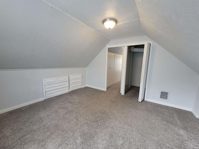 bonus room featuring lofted ceiling, carpet flooring, visible vents, and a textured ceiling